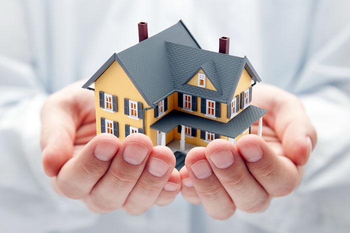 Two hands holding a small model house